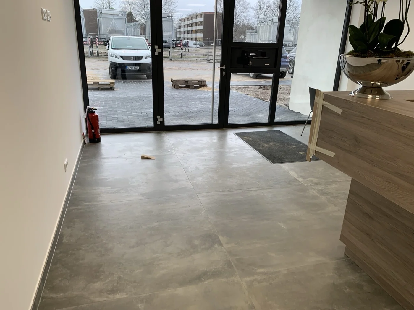 Moderner Eingangsbereich mit großformatigen beigen Bodenfliesen und schwarzen Glastüren