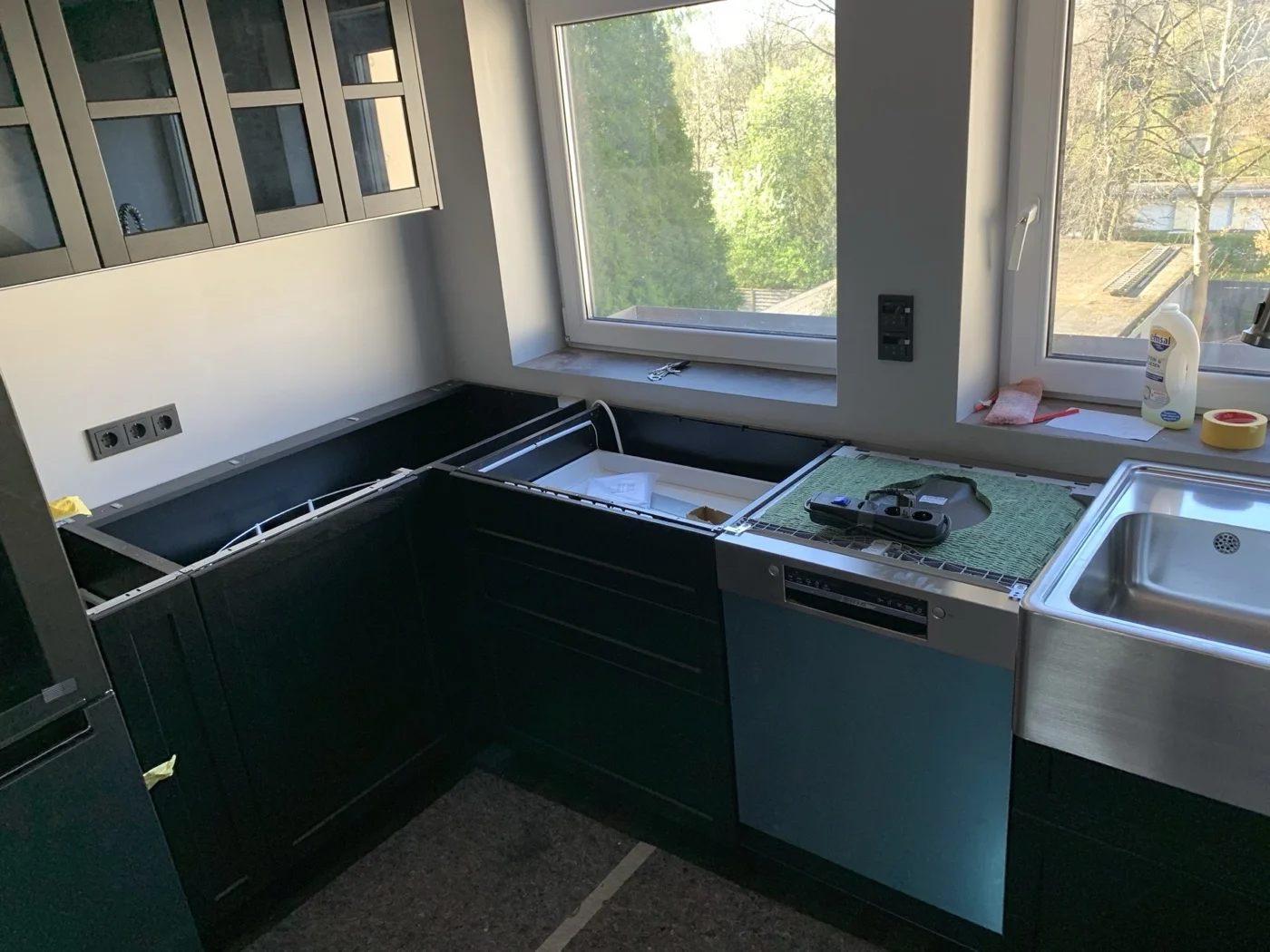 Kücheneinbau mit grünen Hochglanzfronten, Edelstahlgeräten und modernen Eckschränken