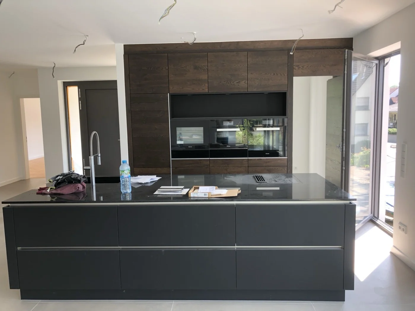 Moderne Küche mit dunklen Holzschränken, großer Kochinsel und Granitarbeitsplatte in anthrazit