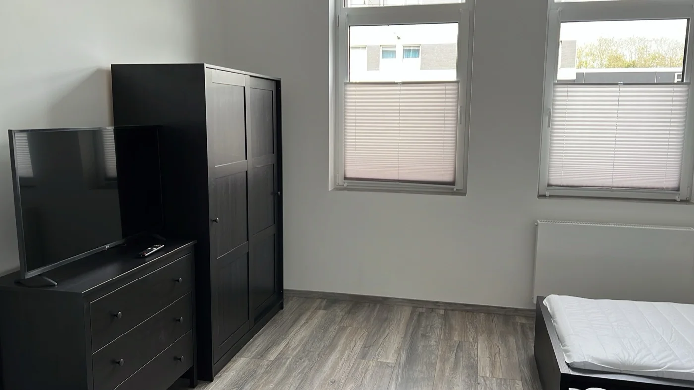 Schlafzimmer mit modernen dunklen Möbeln, Laminatboden in Holzoptik und Plissee-Jalousien