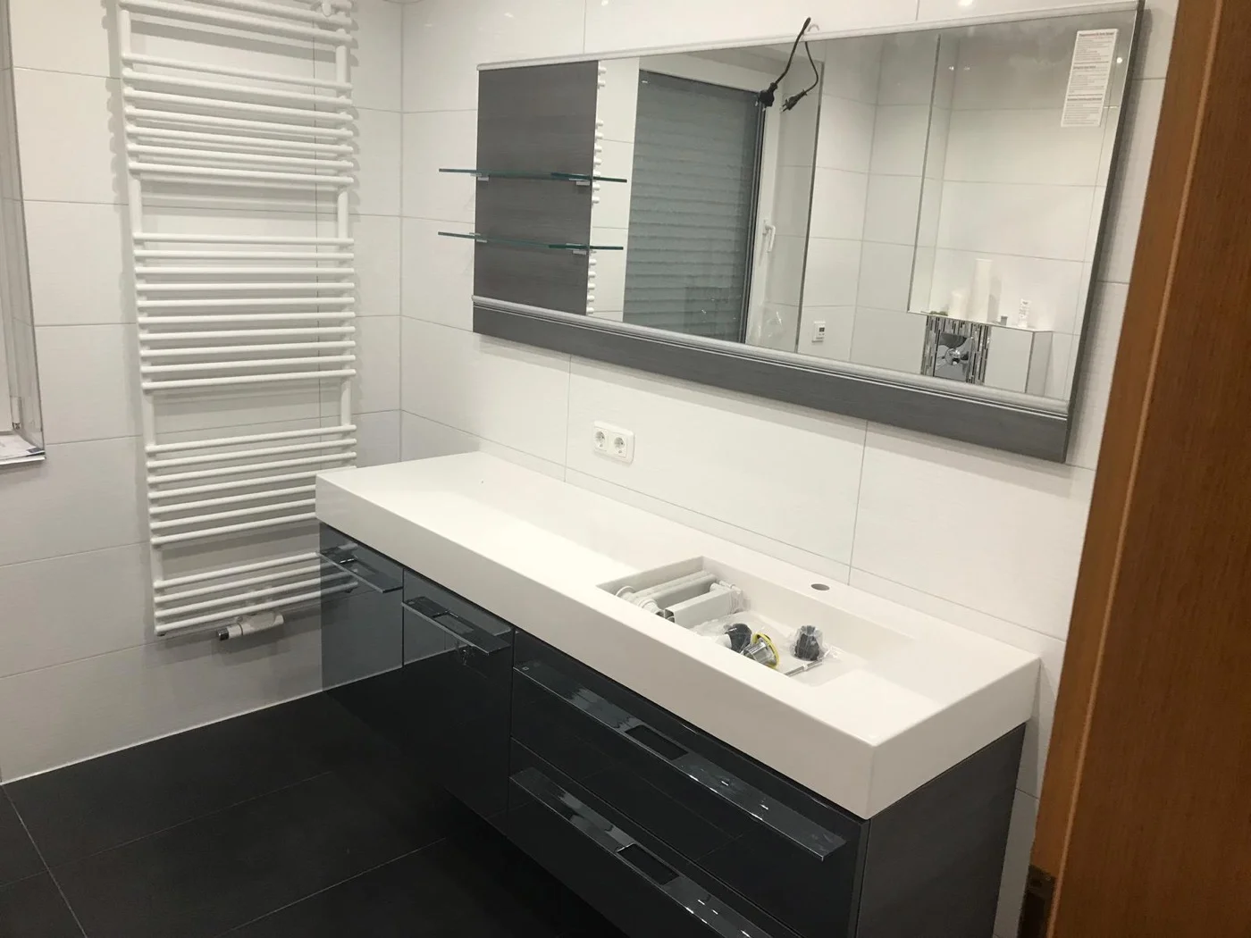 Hochwertiger Waschtischbereich mit großem Wandspiegel, grauem Unterschrank und indirekter Beleuchtung